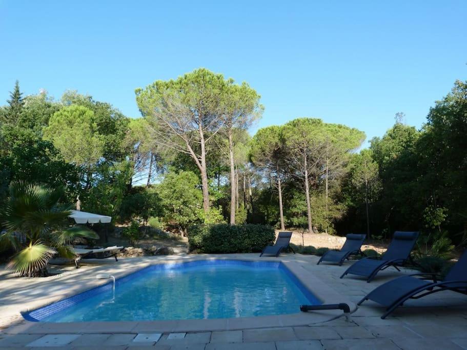 una piscina en un patio con sillas y árboles en Villa romantique avec Poolhaus, en Cotignac