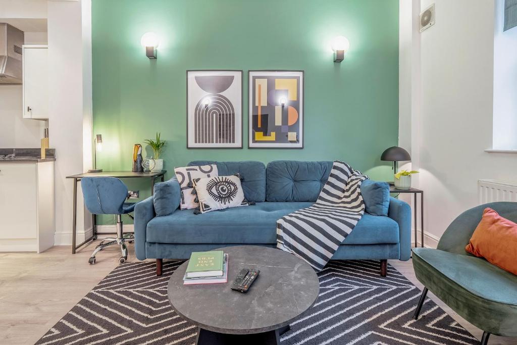 a living room with a blue couch and a table at Kula London - Tower Bridge in London