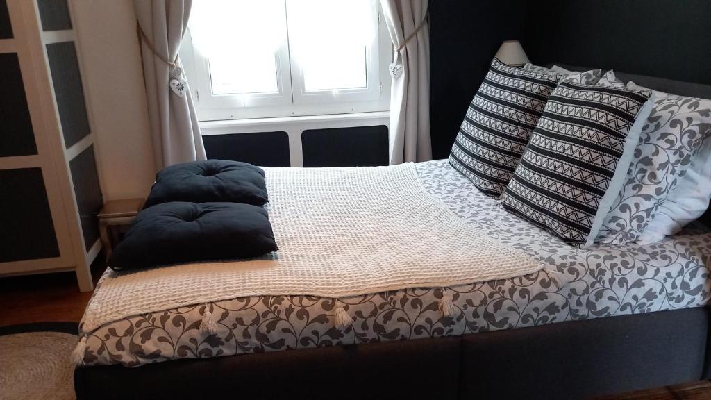 Una cama con almohadas encima y una ventana. en Chambre d'hôte & coin petit-déjeuner, en Camaret-sur-Mer