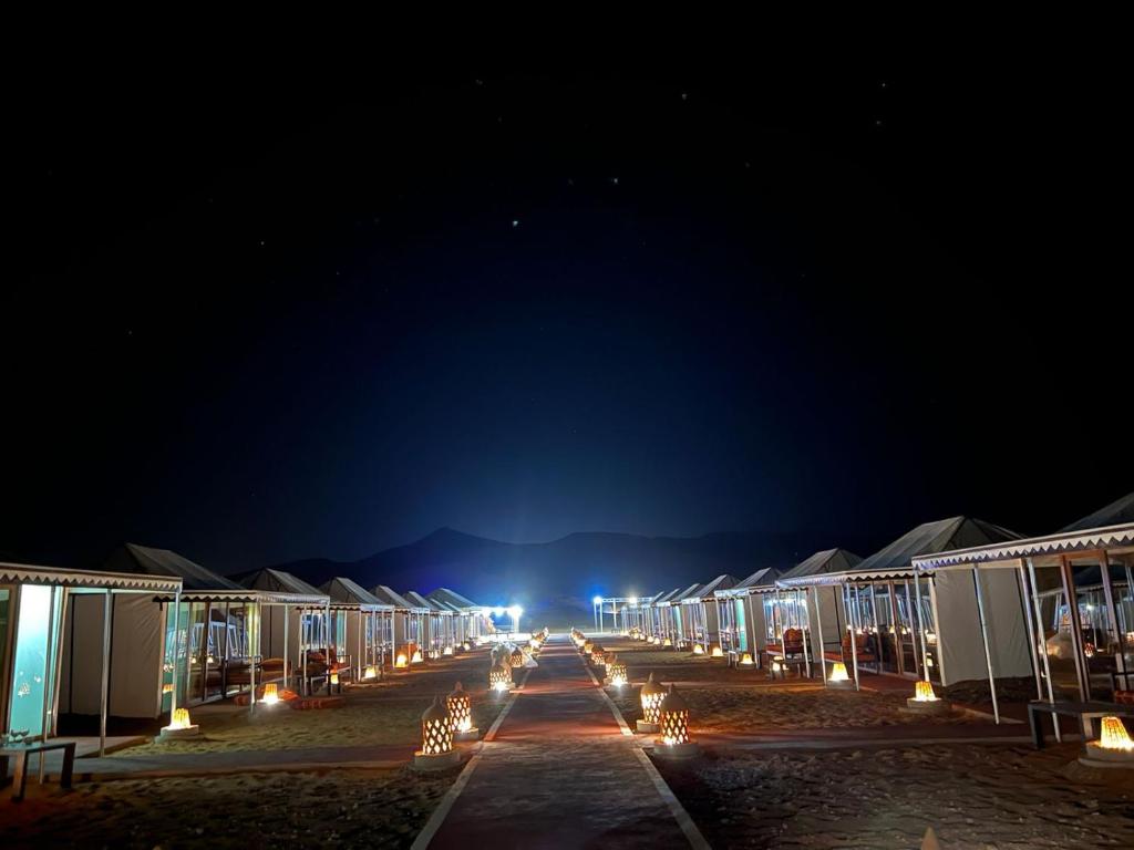una fila de casas por la noche con luces en Merzouga Dunes Luxury Camps, en Merzouga