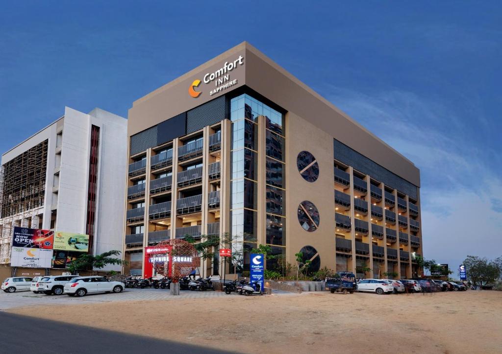 un gran edificio con coches estacionados en un estacionamiento en Comfort Inn Sapphire Chandkheda, Ahmedabad, en Ahmedabad