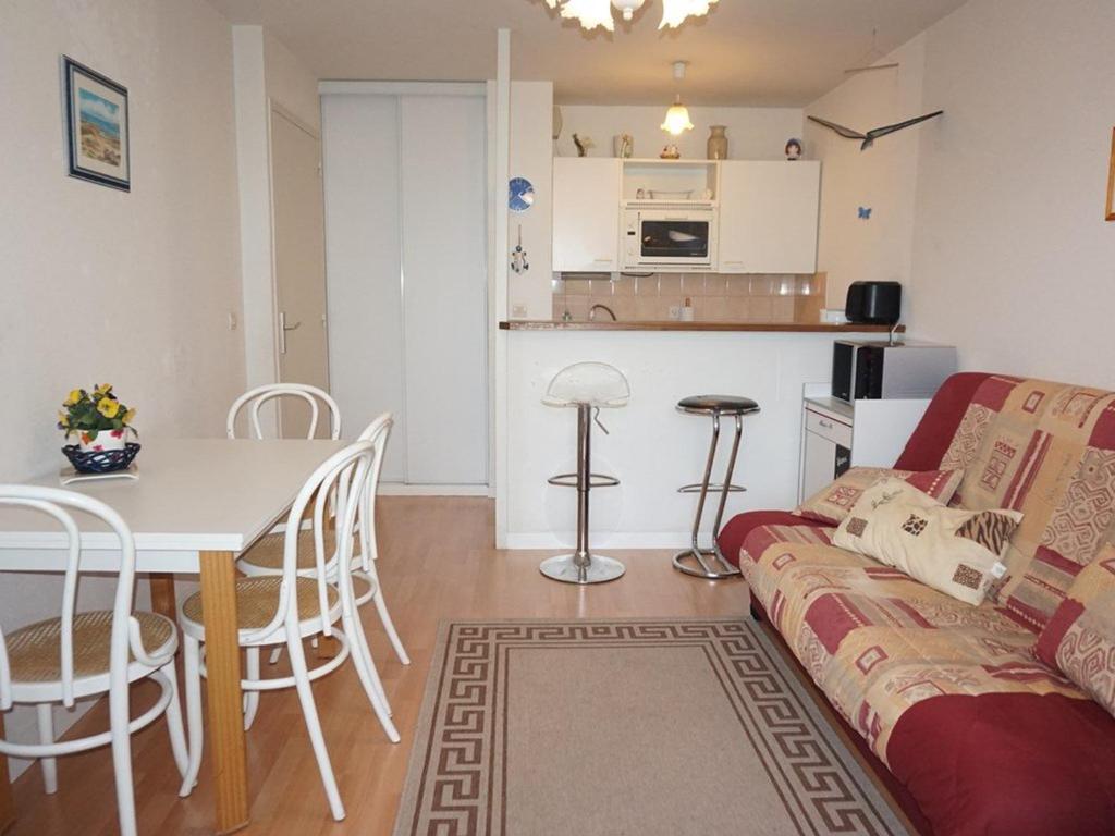 ein Wohnzimmer mit einem Sofa und einem Tisch sowie eine Küche in der Unterkunft Appartement Cabourg, 2 pièces, 4 personnes - FR-1-465-21 in Cabourg