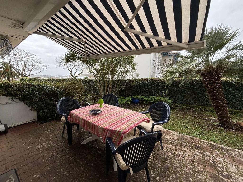 - une table et des chaises sous un parasol sur la terrasse dans l'établissement Appartement Royan avec Terrasse en Bord de Mer - FR-1-494-172, à Royan