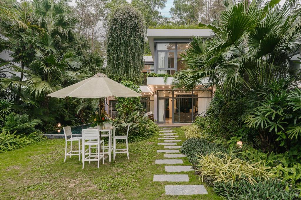 una casa con mesa, sillas y sombrilla en Rosee Villa - Eco Green Villa in Flamigo Dai Lai Resort, en Vĩnh Phúc