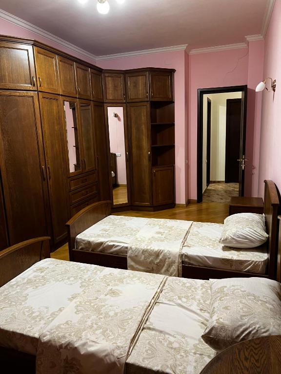 two beds in a room with pink walls and wooden cabinets at Home in Yerevan