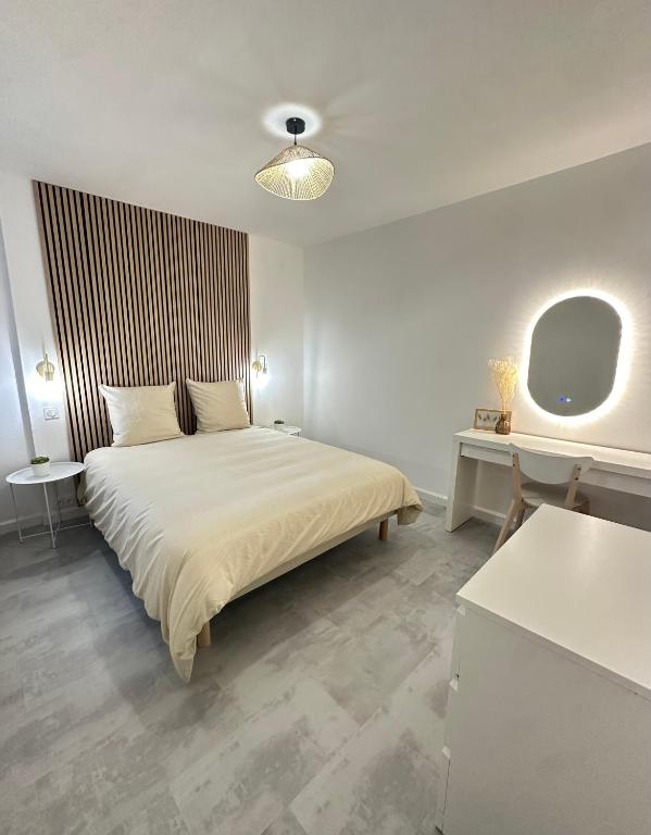 une chambre blanche avec un lit et un miroir dans l'établissement Les Lotus - Joli F2 rénové, à Saumur