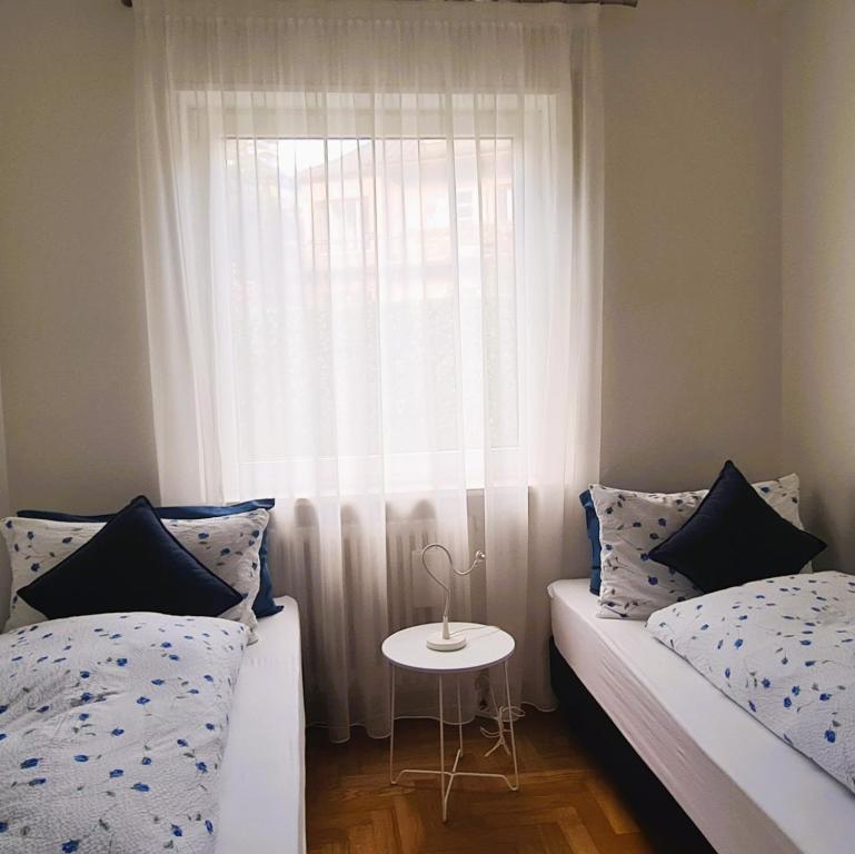 a bedroom with two beds and a window with a table at Appartamento Nadia, bilocale nel verde a 5 minuti dal centro in Merano