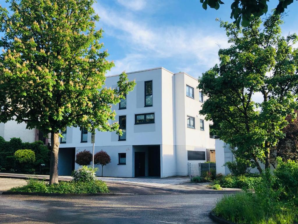 ein weißes Gebäude mit Bäumen davor in der Unterkunft Cube - Ferienhaus mit Garten und Terrasse in Eberbach in Eberbach