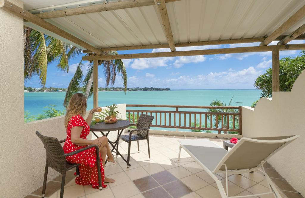 a woman sitting at a table on a patio overlooking the ocean at LAGOON VIEW Résidence in Grand-Baie