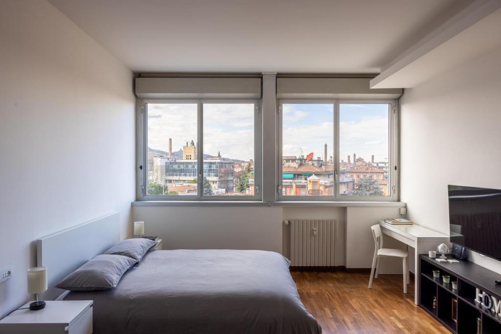 um quarto com uma cama, uma secretária e 2 janelas em Paolo Fabbri Apartment em Bolonha