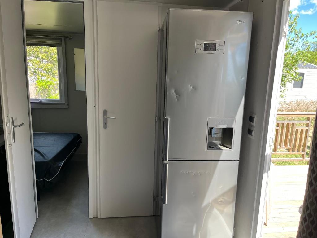 - un réfrigérateur blanc dans une chambre à côté d'une porte dans l'établissement Camping lac des rêves, à Lattes