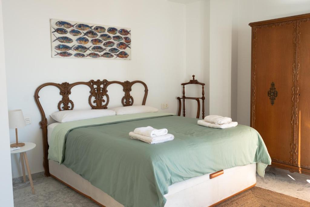 1 dormitorio con 1 cama verde y 2 toallas plegables en Las pirañas, en Melilla