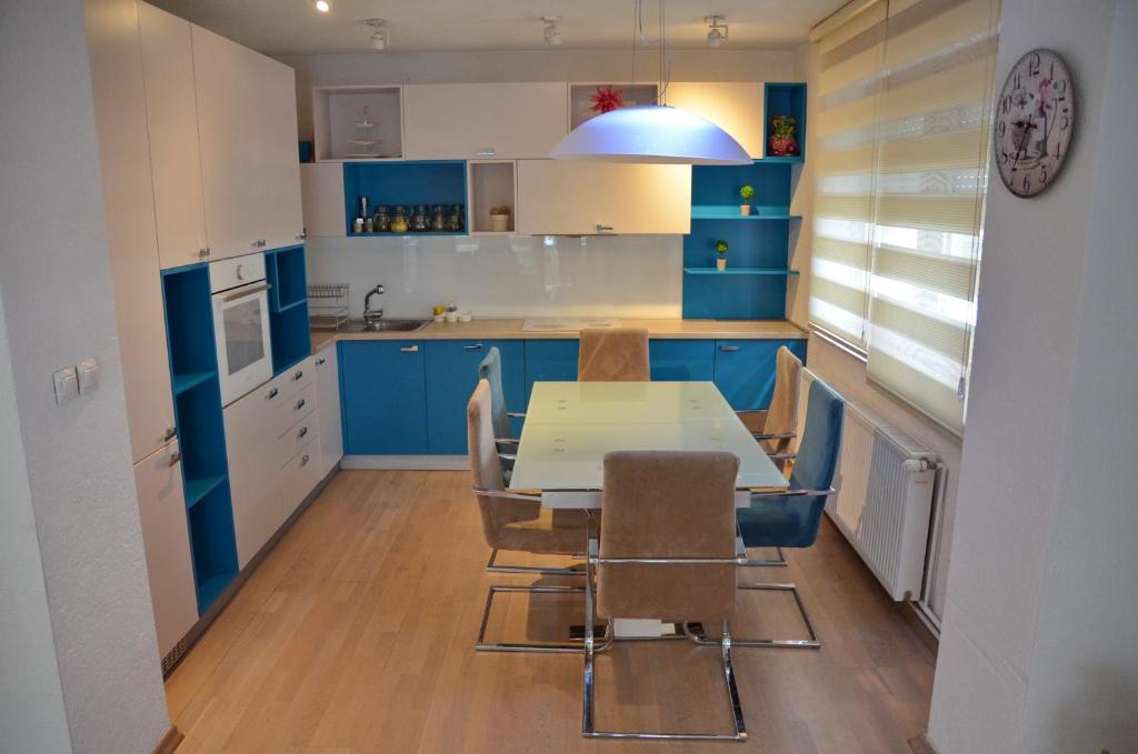 eine Küche mit blauen Schränken sowie einem Tisch und Stühlen in der Unterkunft Feel Good Apartments in Ohrid