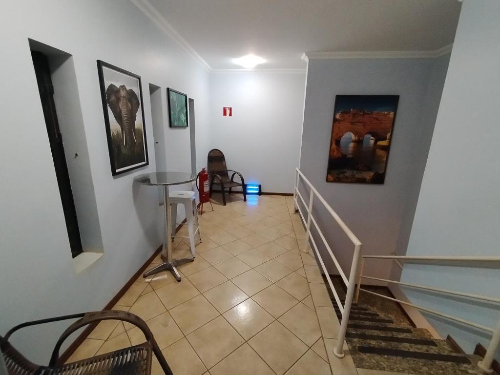 a hallway with stairs with chairs and paintings on the walls at Pousada Indi in Ribeirão Preto