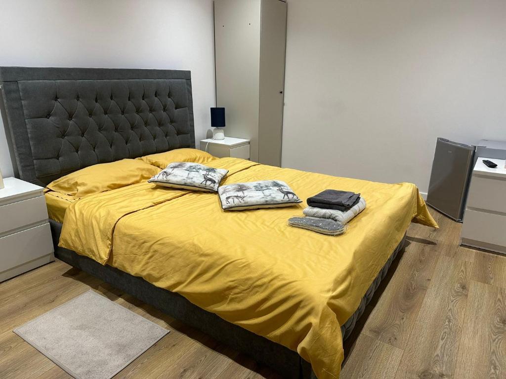 a bedroom with a yellow bed with two towels on it at L-Houses in Dagenham