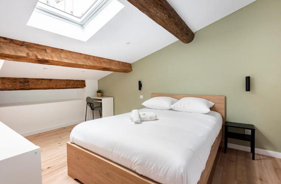 a bedroom with a white bed and a skylight at {St Fée sur les toits} * plein centre Marseille * Clim in Marseille