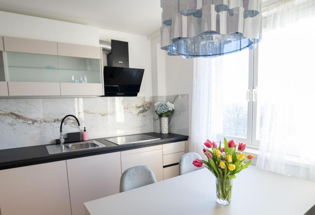 a kitchen with a table with a vase of flowers on it at Central Elite Vista-with parking in Ljubljana