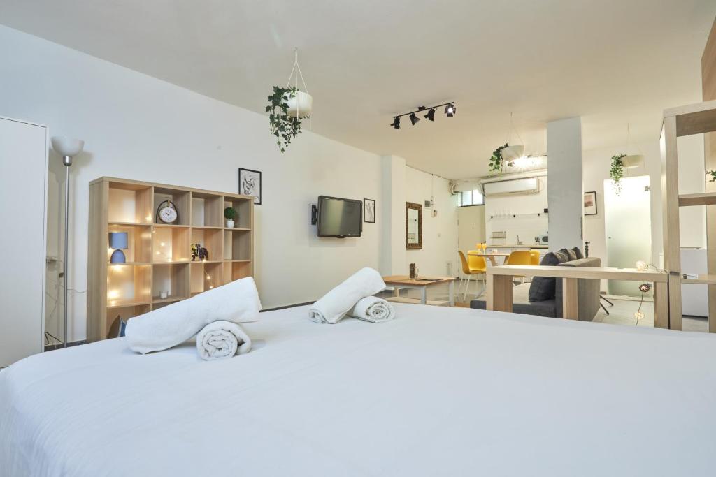 a bedroom with a large white bed and a kitchen at Ran's BIG Artistic Studio in Tel Aviv