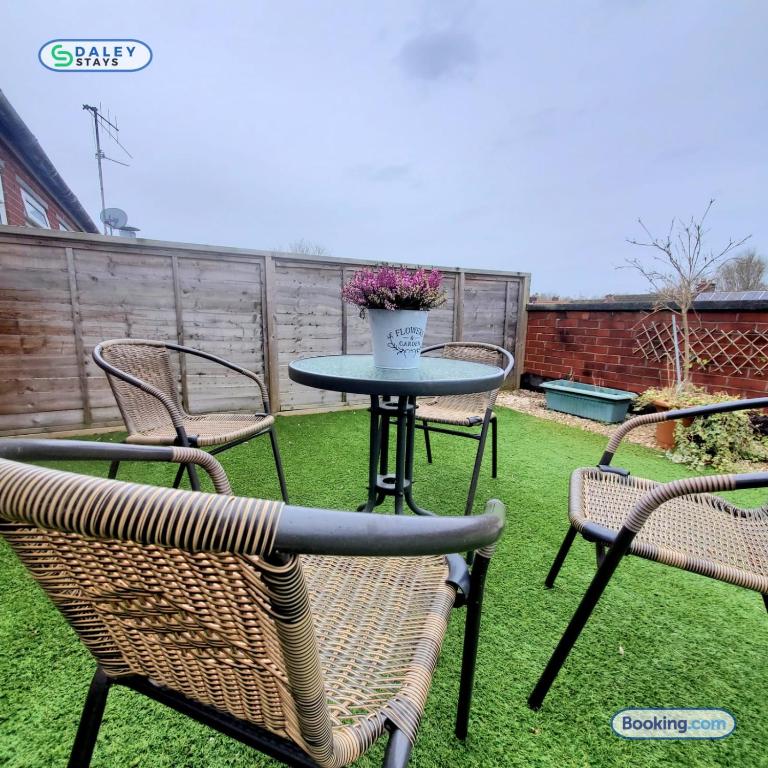 a patio table and chairs with a table and flowers at Cheadle Rooftop Apartment by Daley Stays - Sleep 6 in Cheadle Hulme