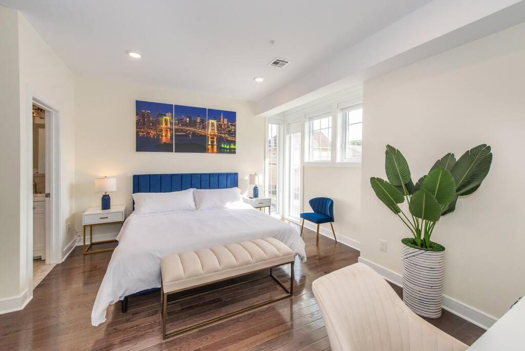 a white bedroom with a bed and a potted plant at Chic Condo-NYC@Fingertips in North Bergen