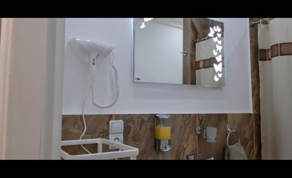 ein weißes Badezimmer mit einem Spiegel und einem Waschbecken in der Unterkunft Apartman 4L in Kladovo