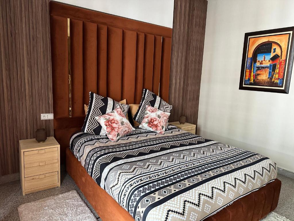 - une chambre avec un lit doté d'une tête de lit en bois et d'oreillers dans l'établissement Appartement la gare Rabat ville, à Rabat