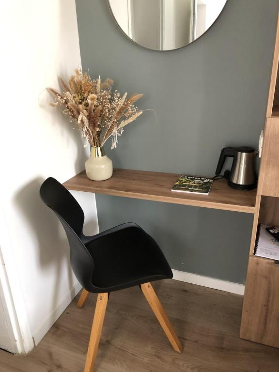 ein schwarzer Stuhl neben einem Schreibtisch mit Spiegel in der Unterkunft Les clés d'à côté - maison d'hôtes proche Rouen in Sotteville-lès-Rouen