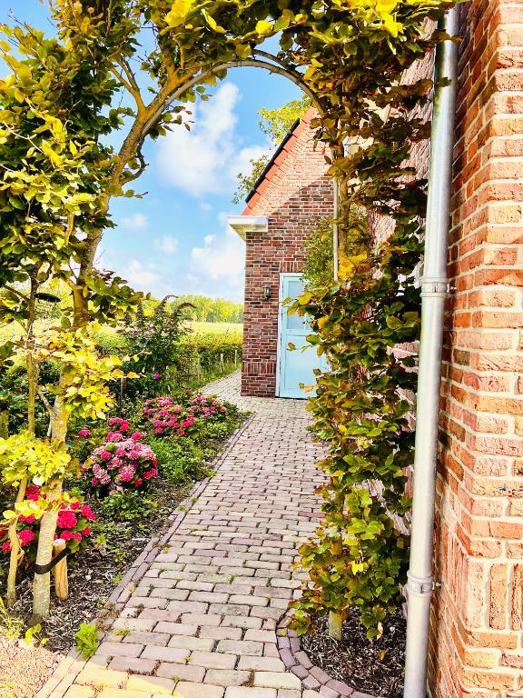 a brick archway with a door in a garden at Beach & Forest Retreat -Domburg- in Oostkapelle