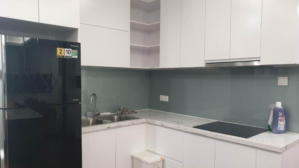 eine Küche mit weißen Schränken und einem schwarzen Kühlschrank in der Unterkunft Home Sweet Home in Haiphong