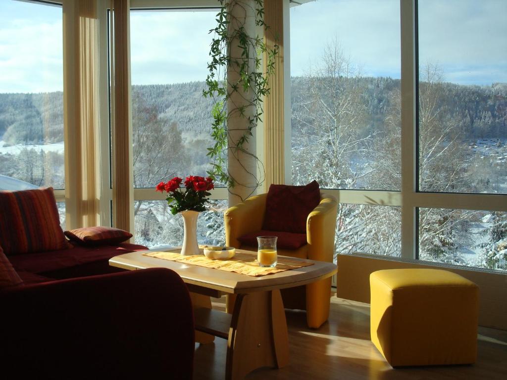een woonkamer met een tafel en stoelen en een groot raam bij Ferienwohnung Bergblick in Zella-Mehlis