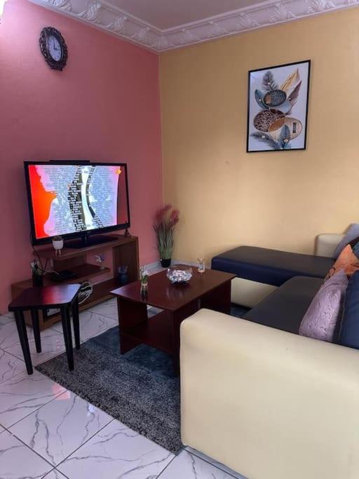 ein Wohnzimmer mit einem Sofa und einem Flachbild-TV in der Unterkunft Appartement meublé Logbessou in Douala