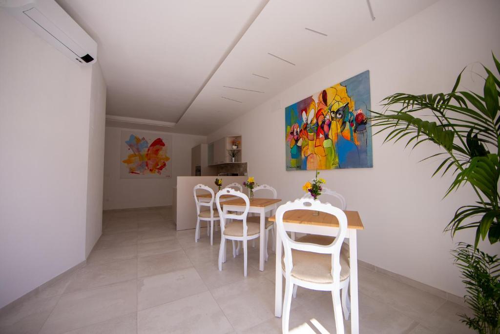 una sala da pranzo con sedie bianche, tavolo e un dipinto di Ars de mar a Martinsicuro