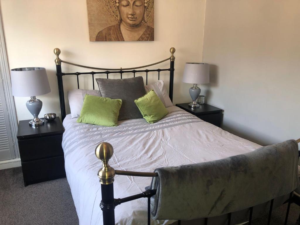 a bedroom with a bed with two lamps and a portrait at Fabulous flat in the fantastic location of Gosforth in Gosforth