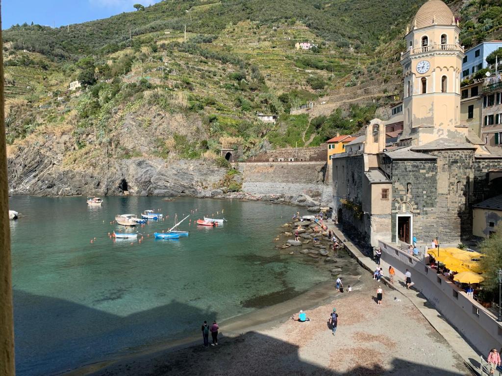 a group of people on a beach with boats in the water at La Marina Vernazza Appartamento Piazza Marconi in Vernazza