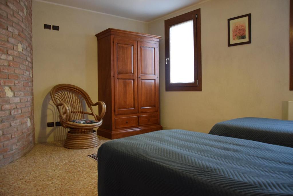 a bedroom with a bed and a chair and a window at Colombara Farmhouse in Mestrino