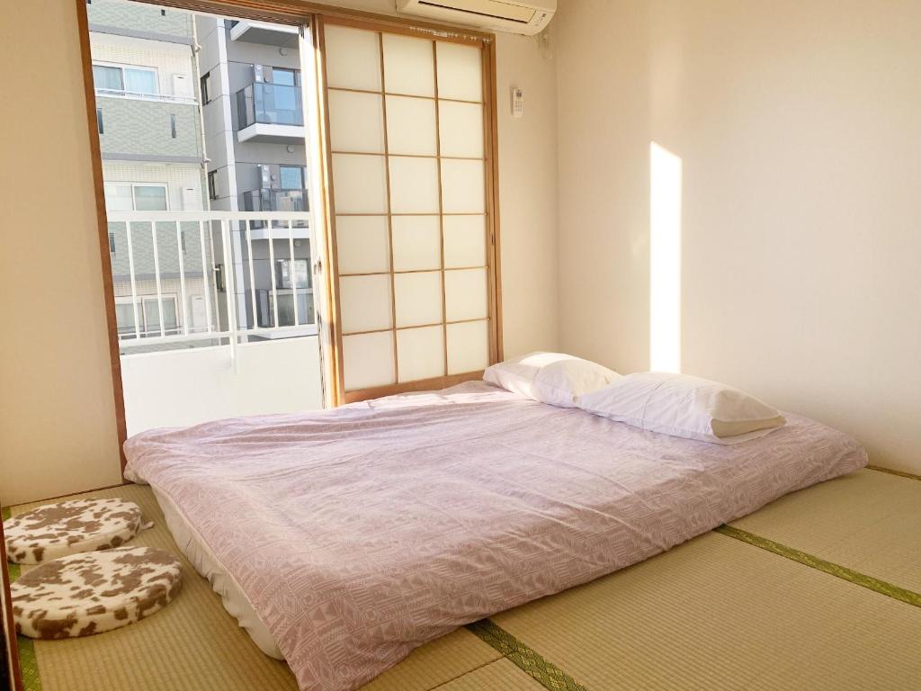 a bed in a room with a large window at 精品新装修60平米2卧室阳光公寓#干湿分离#高速无限制网路#专用电梯直达#3站直达新宿#最大7人#itk501 in Tokyo
