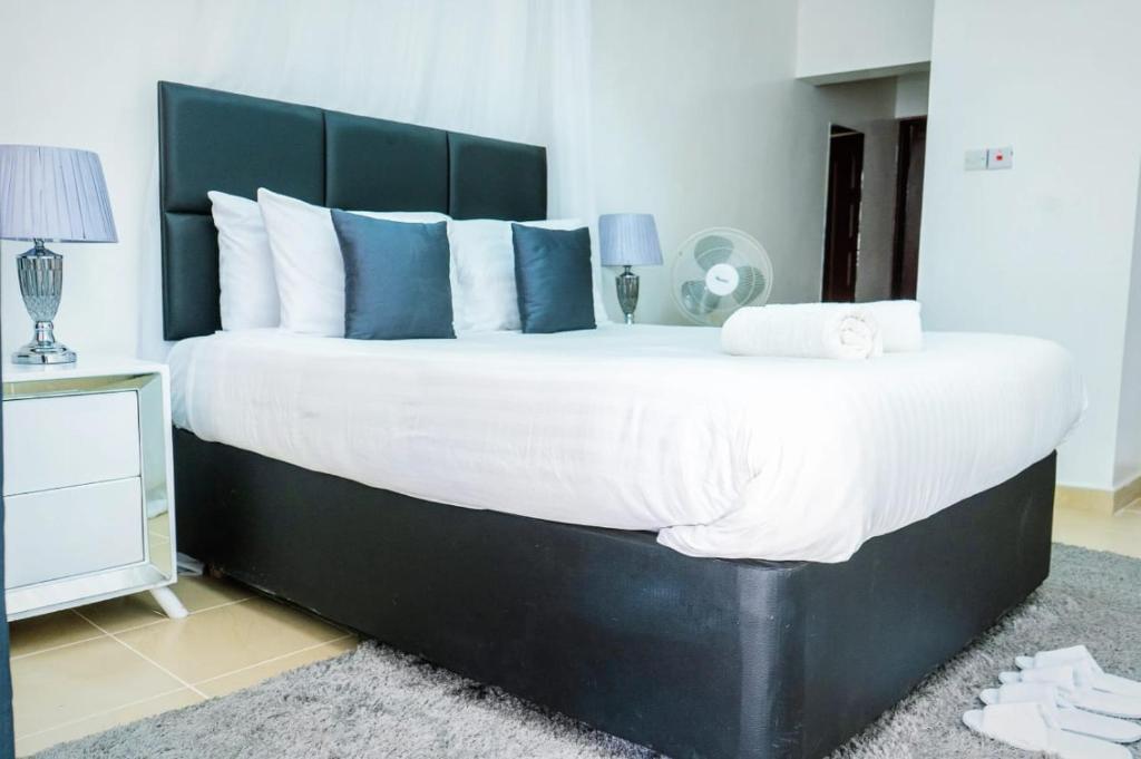 a bedroom with a large bed with blue and white pillows at Sofitel Executive 4 bedrooms Milimani in Kisumu