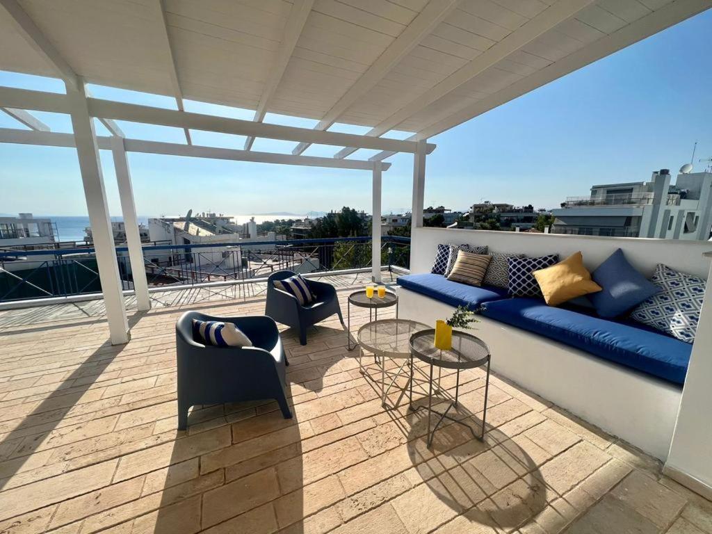 um pátio com um sofá azul e cadeiras numa varanda em Panoramic Terrace with Sunset View - Greecing em Atenas