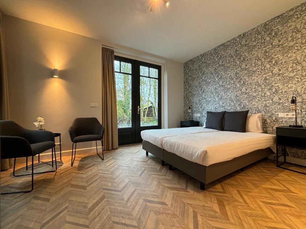 1 Schlafzimmer mit einem großen Bett und 2 Stühlen in der Unterkunft Hof Molenerve - gastenkamers en vakantiewoning in Domburg