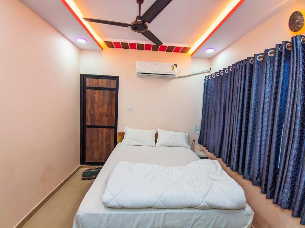 two beds in a room with blue curtains at Hotel Arbuda Palace in Bhuj