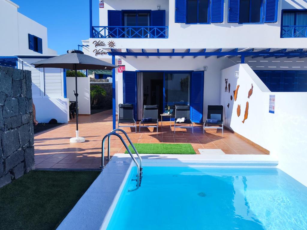 a swimming pool with an umbrella next to a building at Villa Valperal, en Lanzarote in Playa Blanca