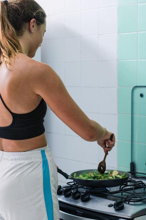 a woman cooking food in a pan on a stove at Nomads Hostel Multicultural & Coworking in Salvador