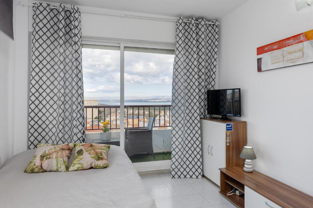 a bedroom with a bed and a window with a view at Estudio Jardín del Mar in Torrevieja