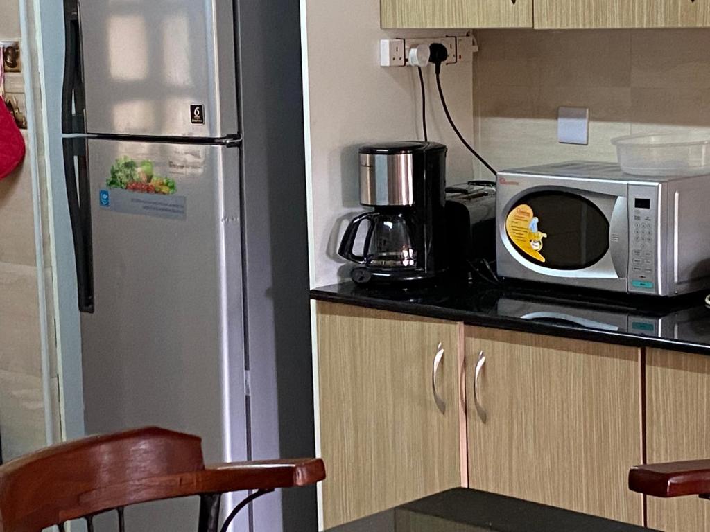 eine Küche mit einer Mikrowelle und einem Kühlschrank in der Unterkunft Runda two bedroom in Nairobi