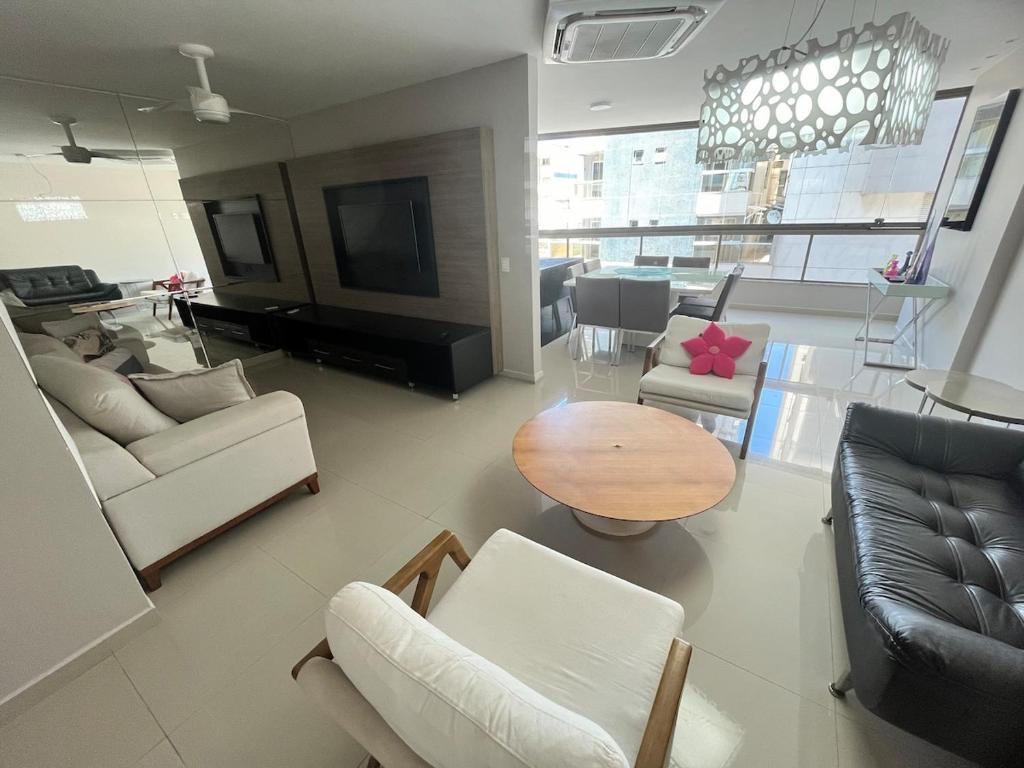 Sala de estar con sofás, mesa y TV en Guarapari Praia - 4 quartos e 2 suítes com ar quiosque 16, en Guarapari