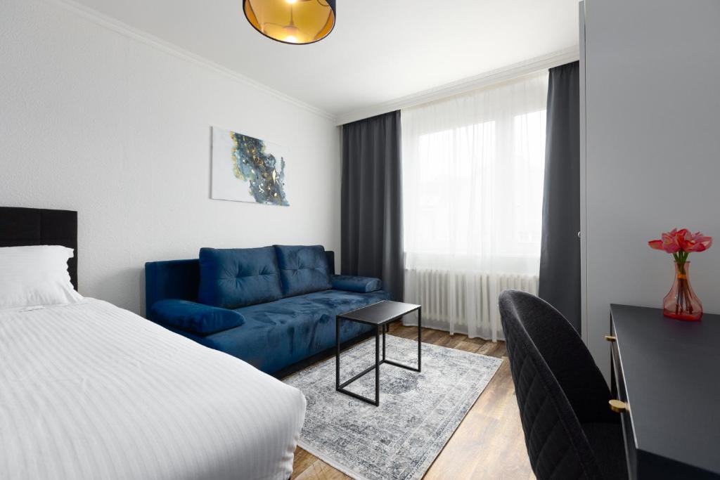 1 dormitorio con 1 cama y 1 sofá azul en Apartment LYLY, en Karlovy Vary