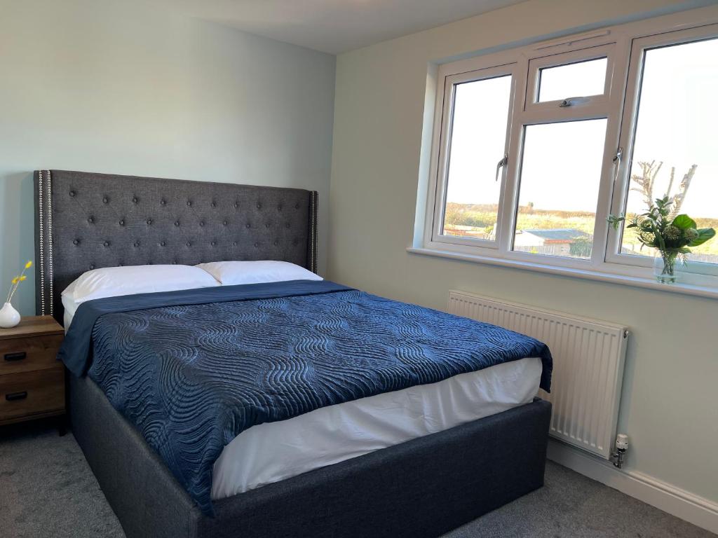 a bedroom with a bed with a blue comforter and two windows at Modern 3 Bed home in Grantham in Grantham