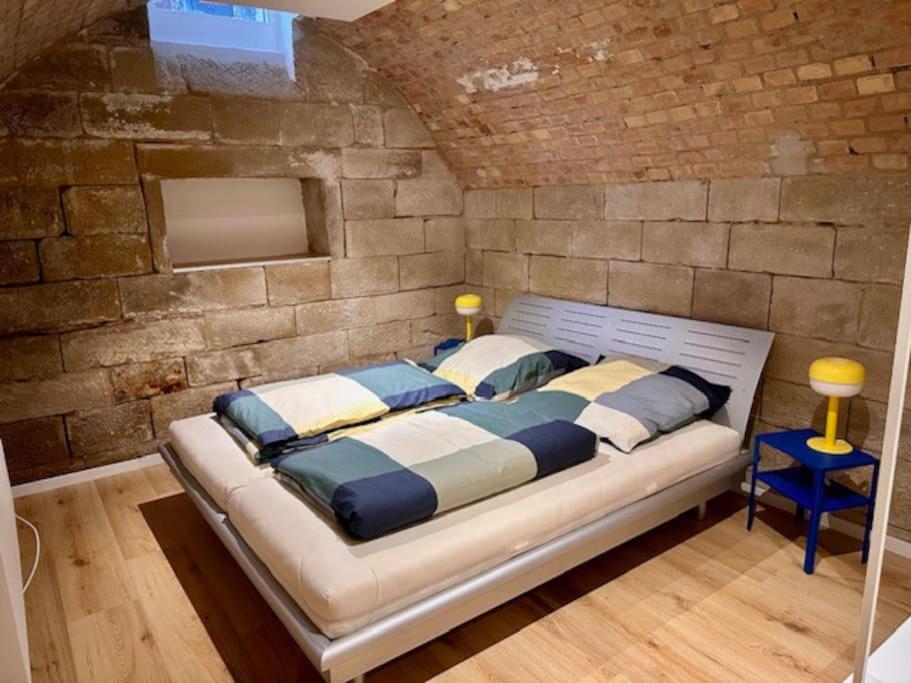 een groot bed in een kamer met een bakstenen muur bij Unique souterrain apartment in Heilbronn