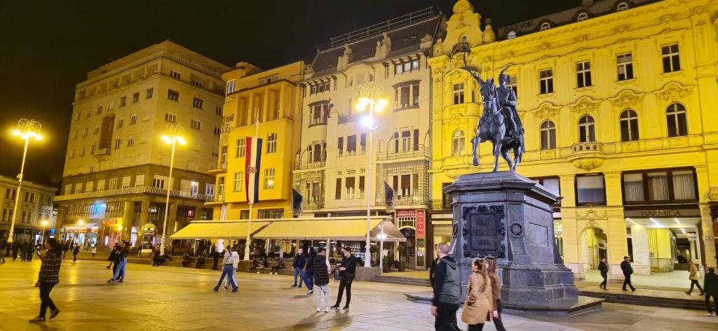 een stadsstraat 's nachts met een standbeeld van een paard bij KUHARIĆ in Zagreb