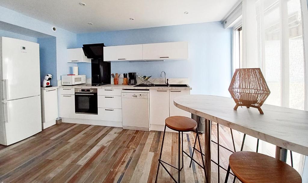 a kitchen with white appliances and a wooden table at Saint-Raphaël-Front de Mer-WIFI-CLIM in Saint-Raphaël